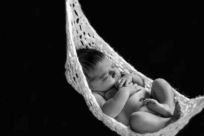 black and white photo of newborn in baby knit hammock photographed in studio in Rochester, Minnesota