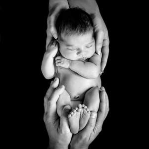 black and white photo of newborn in parents hands photographed in studio in Rochester, Minnesota